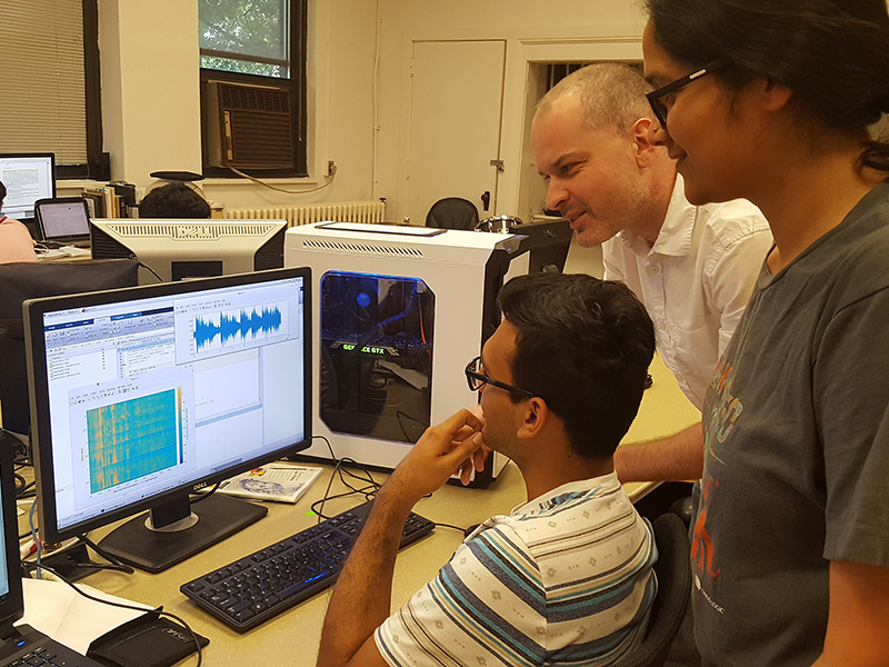 Three people look at a computer screen.