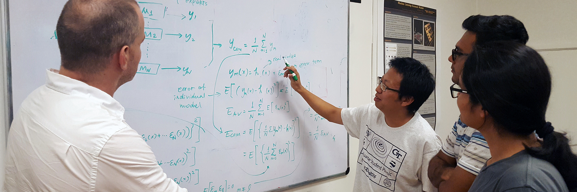 Four people gather at a whiteboard.